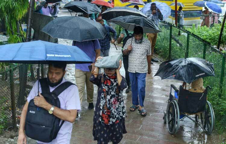 বৃষ্টি উপেক্ষা করেই ছাতা মাথায় ছুটছেন মানুষজন। ছবি: মাহবুব আলম