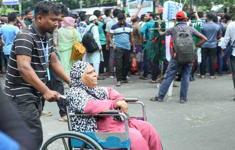 গাড়ি না পেয়ে হাসপাতাল থেকে হুইল চেয়ারে করেই মাকে নিয়ে ফিরছেন ছেলে। ছবি: মাহবুব আলম