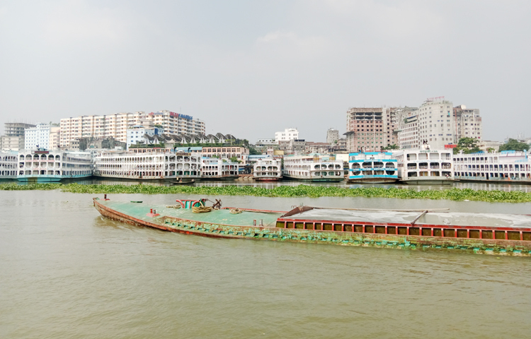 ঢাকার বুড়িগঙ্গার বুক চিড়ে চলাচল করে লঞ্চ। একই সঙ্গে নদীতে বাল্ক হেডে করে বালি নিয়ে যাচ্ছে। পেছনে সদরঘাটে লঞ্চ নোঙর করা আছে। ছবি: ফাত্তাহ তানভীর রানা