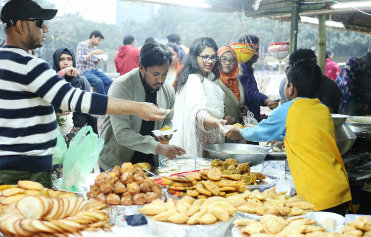 নিজের পছন্দ মতো পিঠা খাচ্ছেন উৎসবে আসা দর্শনার্থীরা। ছবি: মাহবুব আলম