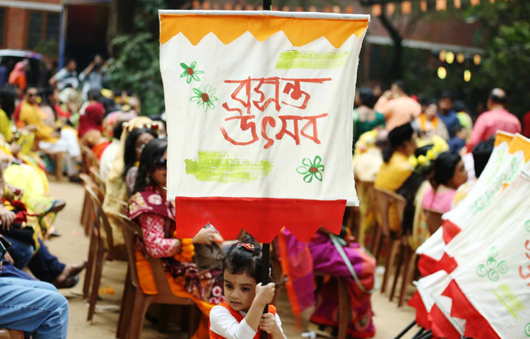 বসন্তের ব্যানার ধরে দাঁড়িয়ে আছে ছোট্ট একটি শিশু। ছবি: মাহবুব আলম