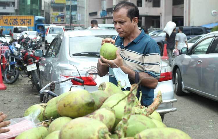 ডাবের পানিতে তৃষ্ণা মেটাচ্ছেন পথচারীরা। ছবি: মাহবুব আলম