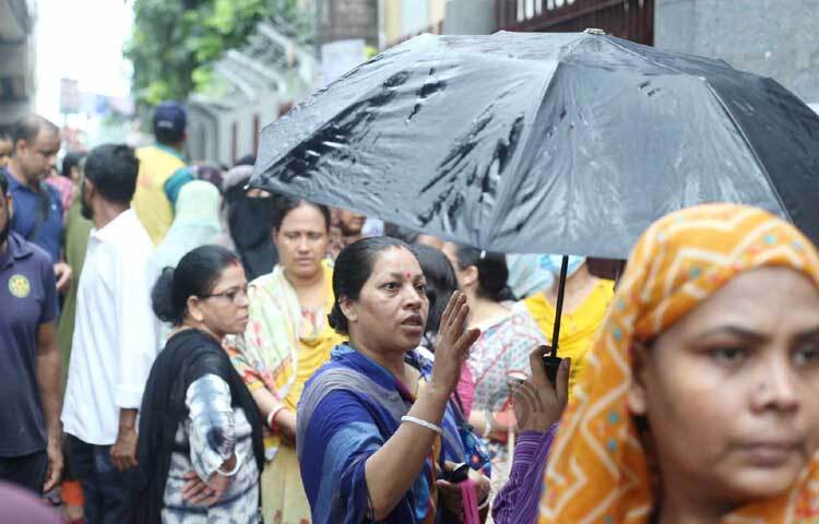 কেন্দ্রের বাইরে ছাতা মাথায় দাঁড়িয়ে আছেন অভিভাবকরা। ছবি: মাহবুব আলম