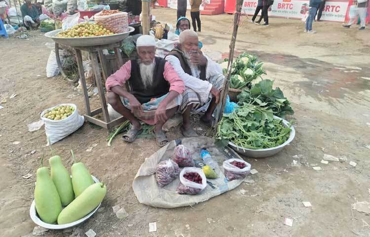 মেলার বাইরে তাজা সবজি নিয়ে বসে আছেন দুই বৃদ্ধ।