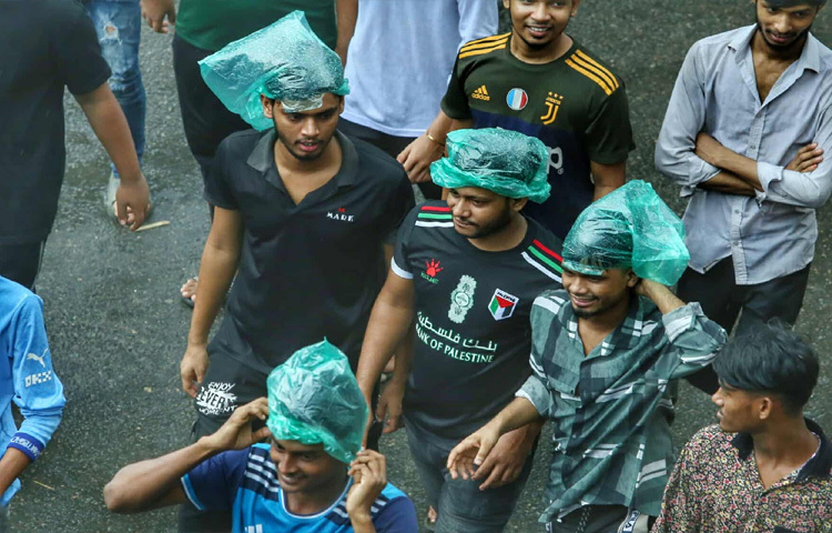মাথায় পলিথিন টেনে, ভেজা গায়ে অনেকেই রাস্তায় দাঁড়িয়ে রয়েছেন দলীয় পতাকা হাতে।
