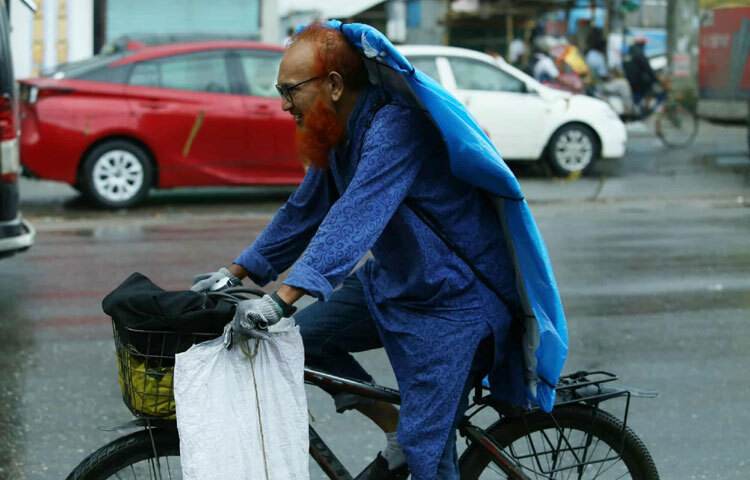 বৃষ্টির দিনেও থেমে নেই কারোর পথচলা। হাসিমুখে সাইকেলে চেপে কাজে বেরিয়েছেন তিনি।