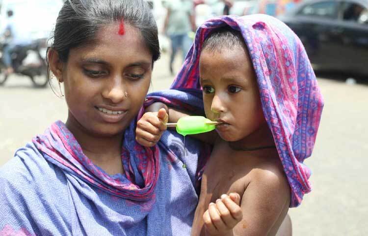 মাথায় ওড়না দিয়ে ছেলেকে আইসক্রিম খাওয়াচ্ছেন মা। ছবি: মাহবুব আলম