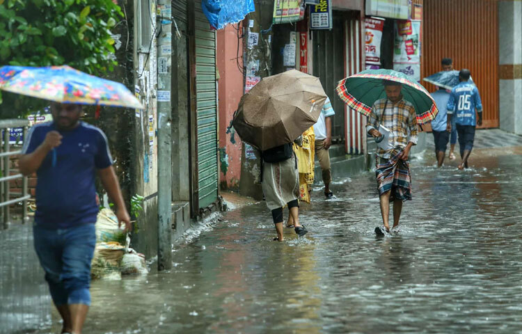 অফিসগামী অনেকে ছাতা মাথায় ভিজে যাচ্ছেন, কেউ আবার জুতো হাতে নিয়েই হেঁটে চলেছেন। কারও মুখে বিরক্তি, কারও চোখে ক্লান্তি, তবু জীবনের ছন্দ থেমে নেই।