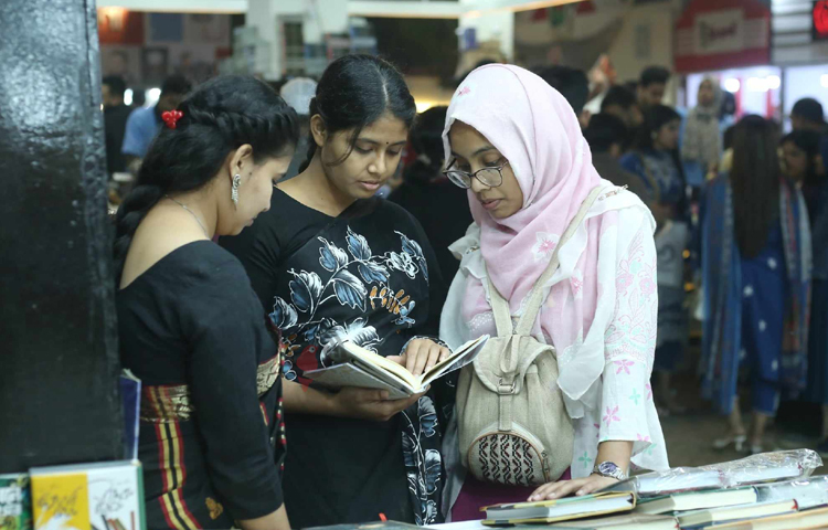 মেলায় নতুন বই হাতে তিন বইপ্রেমী। ছবি: মাহবুব আলম