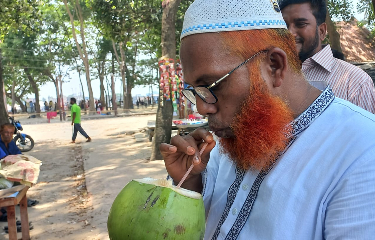 ডাবের পানিতে তৃষ্ণা মেটাচ্ছেন বৃদ্ধ। ছবি: শরিফুল ইসলাম