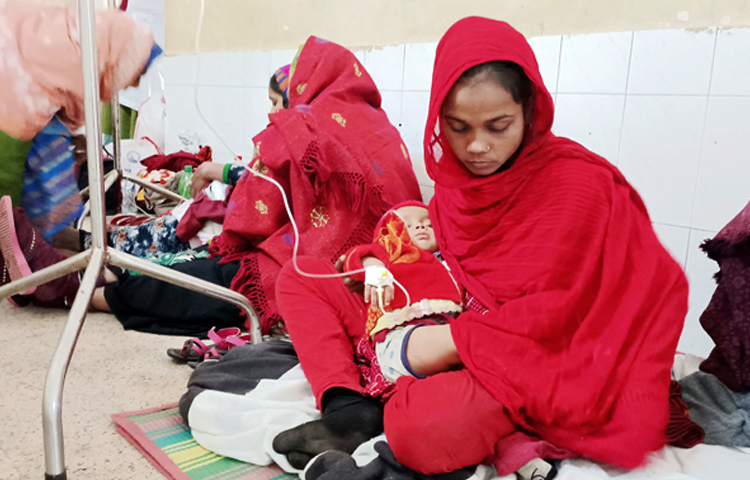 চাঁপাইনবাবগঞ্জে বেড়েছে শীতের তীব্রতা। এতে শিশু ও মধ্যবয়সী নারীরা আক্রান্ত হচ্ছে ডায়রিয়া-নিউমোনিয়া ও ভাইরাস জনিত জ্বরে। অতিরিক্ত রোগীর চাপ সামলাতে হিমশিম খাচ্ছেন চিকিৎসকরা। হাসপাতালে বেড না পেয়ে রোগীদের চিকিৎসা নিতে হচ্ছে মেঝেতে। ছবি: সোহান মাহমুদ