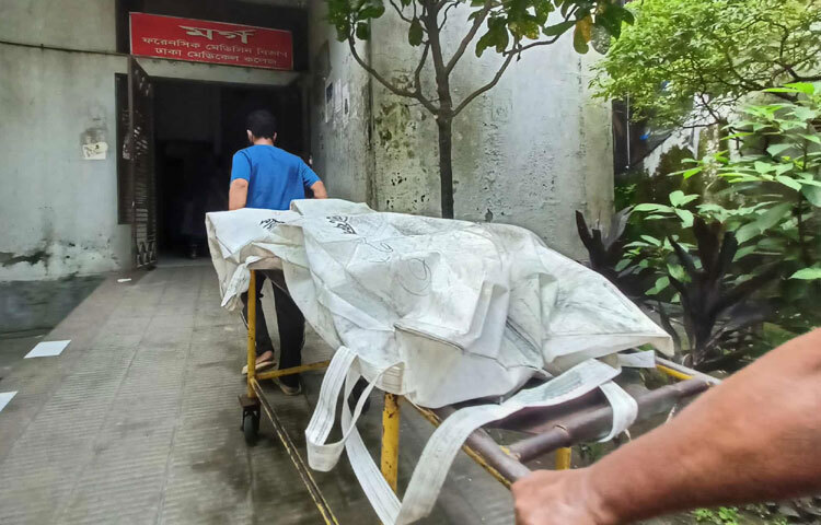 মর্গের বাতাসে মিশে আছে পোড়া গন্ধ আর হাহাকার। মর্গের ভেতর কাজ করছেন স্বাস্থ্যকর্মী ও পুলিশের সদস্যরা। কেউ নম্বর লিখছেন ব্যাগের ওপর, কেউ আবার ট্যাগ লাগাচ্ছেন শনাক্ত করা দেহে। বাইরে অপেক্ষায় স্বজনরা-প্রত্যেকে যেন মৃত্যুর দ্বারে দাঁড়িয়ে আছেন, হাতে প্রিয়জনের একটুখানি চিহ্ন।