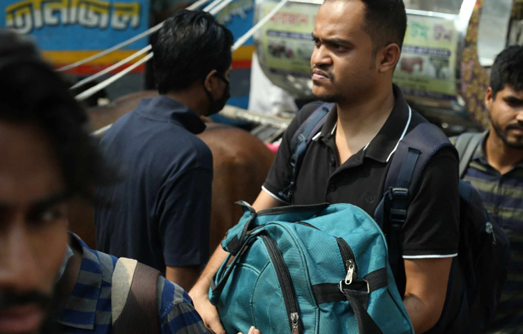 বাসের জন্য অপেক্ষা করছেন এক যাত্রী।