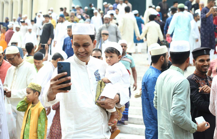 সন্তানকে কোলে নিয়ে নামাজ পড়তে এসেছে বাবা। ছবি: মাহবুব আলম