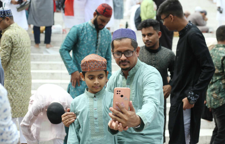 নামাজ শেষে ছেলেকে নিয়ে সেলফিতে স্মৃতি ধরে রাখছেন বাবা। ছবি: মাহবুব আলম