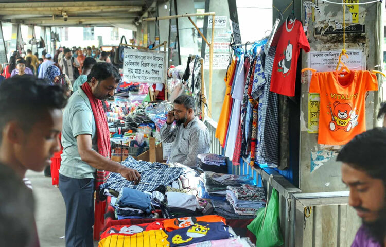 কিন্তু দিন গড়াতেই চিত্র পাল্টে যায়। আজ সেই ফুটওভার ব্রিজে দাঁড়ালেই দেখা যায়, প্রতিটি ধাপ যেন দোকানপাটে ভরে গেছে। জামাকাপড়, মোবাইল অ্যাকসেসরিজ, খাবার-কি নেই সেখানে?