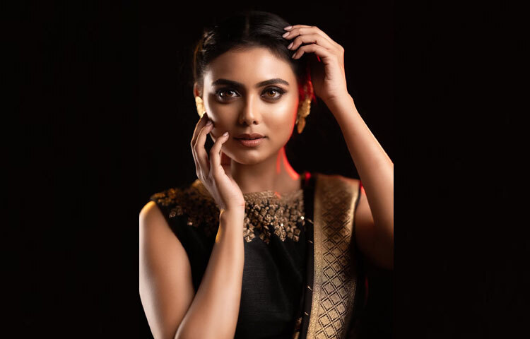 ইধিকার মেকআপও তার মতোই পরিমিত। বেছে নিয়েছেন ন্যুড বেজ টোন, যা কালো পোশাকের গভীরতাকে আরও উজ্জ্বল করেছে। চোখে হালকা কাজল, ঠোঁটে ন্যুড শেড লিপস্টিক, আর চুল বাঁধা হয়েছে পরিপাটি মিডল বান স্টাইলে। সব মিলিয়ে লুকে এসেছে সহজ অথচ রাজকীয় এলিগ্যান্স।