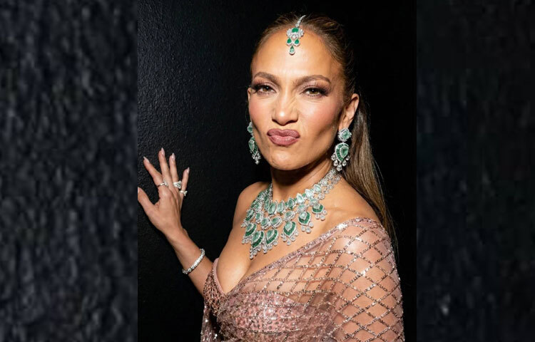 এসিমেট্রিক ড্রেপিং শাড়িটিকে অর্ধেক দোপাট্টা, অর্ধেক গাউনের মতো রূপ এনে দিয়েছে; আর স্কাল্পটেড স্ট্র্যাপলেস বডিসে ফুটে উঠেছে জেনিফারের সিগনেচার সিলুয়েট।