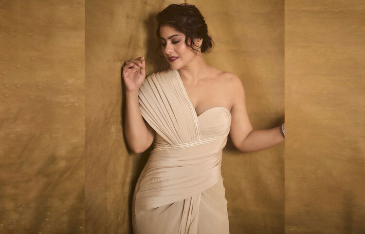 গাউনটির বিশেষত্ব ছিল এর অভিনব নকশা। সফট ন্যুড টোনের এই আউটফিটটি মূলত একটি একরঙা শাড়ি, যা কোরসেটেড বডিসের সঙ্গে গাউনের মতো ড্রেপ করা হয়েছে। ওয়ান-শোল্ডার প্লিটেড স্টাইল এতে এনে দিয়েছে বাড়তি সৌন্দর্য।