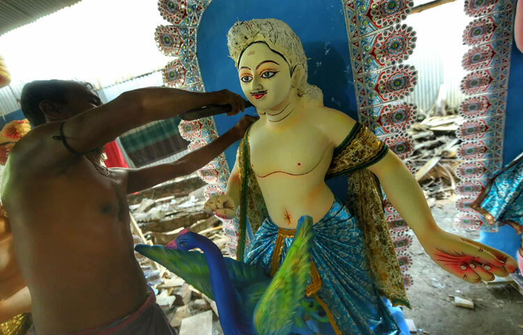 Another group of craftsmen are finishing painting and dressing the idol.