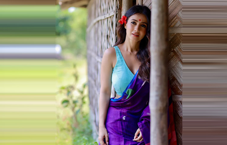 জবা ফুল কানে গোঁজা, চুলে হালকা কার্লস, আর মুখে সেই চেনা হাসি যা যেকোনো মুহূর্তকে করে তোলে স্নিগ্ধ। চোখে ঘন কাজল, লাল টিপ, আর স্টেটমেন্ট আংটির সঙ্গে কোমরে পরা মিনিমাল ডিজাইনের বিছা সব মিলিয়ে এক নিখুঁত এথনিক সৌন্দর্যের প্রতীক হয়ে উঠেছেন মনামী।