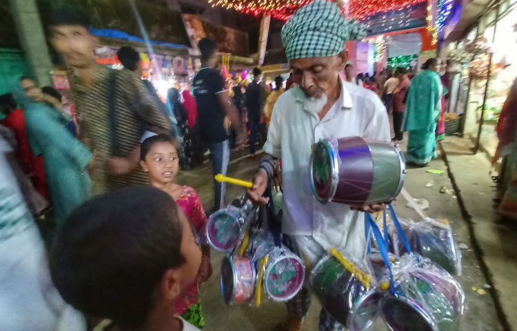 পূজা দেখতে এসে কেউ মিষ্টি খাচ্ছেন, কেউ কিনছেন খেলনা, আবার কেউ শুধু ভিড়ের আনন্দ উপভোগ করছেন।