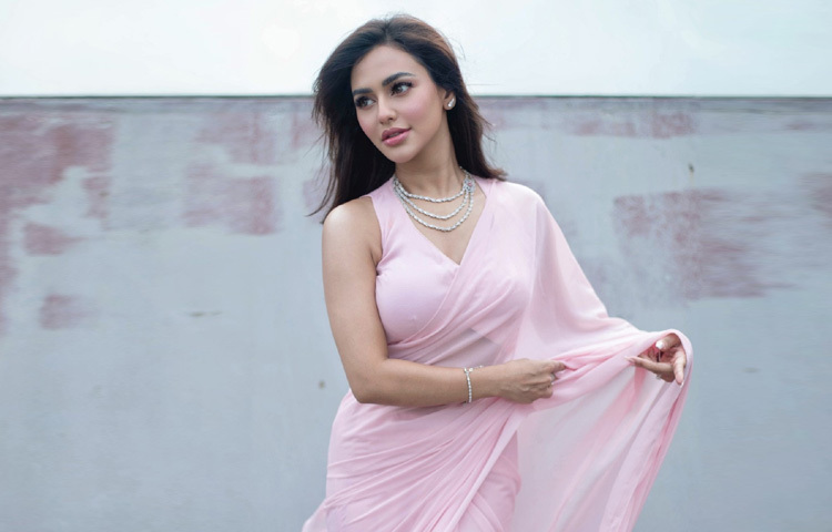 মেকআপেও ছিল এক মৃদু মাধুর্য। গালে সফট পিঙ্ক ব্লাশ, চোখে হালকা স্মোকি টোন আর ঠোঁটে স্নিগ্ধ গোলাপি লিপস্টিক-সব মিলিয়ে এক নিবিড় কোমলতা। চুল ছিল খোলা, স্বাভাবিক ঢঙে, যেন পুরো লুকে মিশে আছে প্রকৃতির অনায়াস সৌন্দর্য।