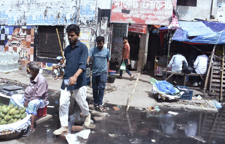 চারদিকে ভেসে বেড়াচ্ছে দুর্গন্ধ, পচা পানির স্রোত গড়িয়ে যাচ্ছে রাস্তায়। পাশ দিয়ে হেঁটে যাওয়া অনেক পথচারী নাক চেপে হাঁটছেন, কেউ কেউ জুতা তুলে হাতে নিয়ে হাঁটছেন, আবার অনেকেই রাস্তার মাঝ দিয়ে চলতে বাধ্য হচ্ছেন, যা একদিকে ঝুঁকিপূর্ণ, অন্যদিকে যানজটও সৃষ্টি করছে।
