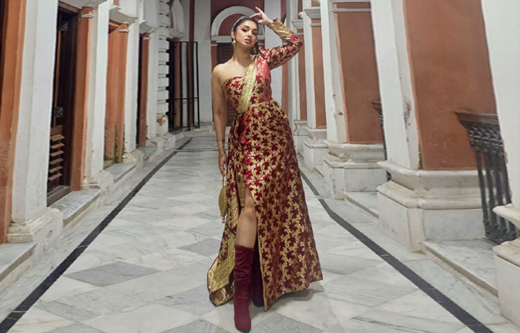 জুতায়ও মিলিয়েছেন নতুনত্ব, রুশ নি-হাই হিল বুটে পাওয়া গেছে সাহসী কিন্তু স্টাইলিশ এক্সপ্রেশন। হাতে রাখা সোনালি ব্যাগ পোশাকের সঙ্গে দারুণ মানিয়েছে