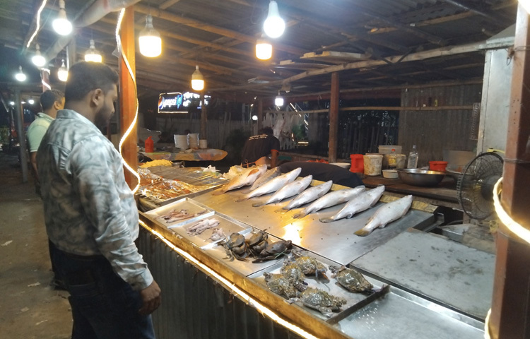 একপাশে সামুদ্রিক মাছের বারবিকিউ চিংড়ি, কাঁকড়া, স্যামন, কোরাল, লবস্টার-সবই সরাসরি গ্রিল হয়ে হাজির হচ্ছে প্লেটে। আরেকপাশে বসে ‘বিথির মা’র পিঠা ঘর, যেখানে আতপ চালের চিতই আর চাপটি পিঠা গরম গরম ভাজা হচ্ছে।