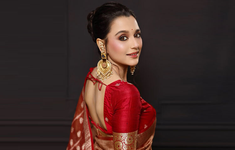 শাড়ির সঙ্গে মিলিয়ে সাবিলা পরেছেন লাল বেনারসী ব্লাউজ, যার ব্যাকলেস ডিজাইন ও স্ট্রিং ডিটেইলস নজর কাড়ার মতো।