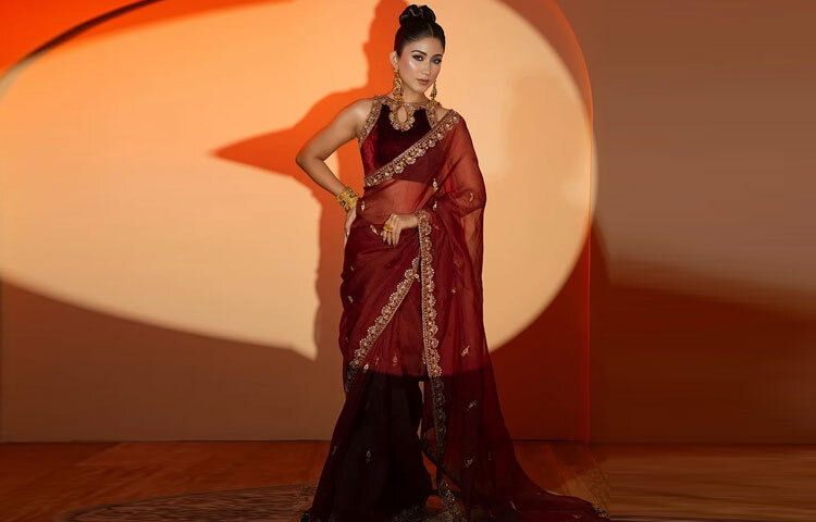 মেরুনের গভীর রঙে মিশেছে সোনালি জরি ও সিকুইনের ঝলমলে কারুকাজ শাড়ির পাড়জুড়ে যেন ফুটে উঠেছে ফ্লোরাল আভিজাত্য।