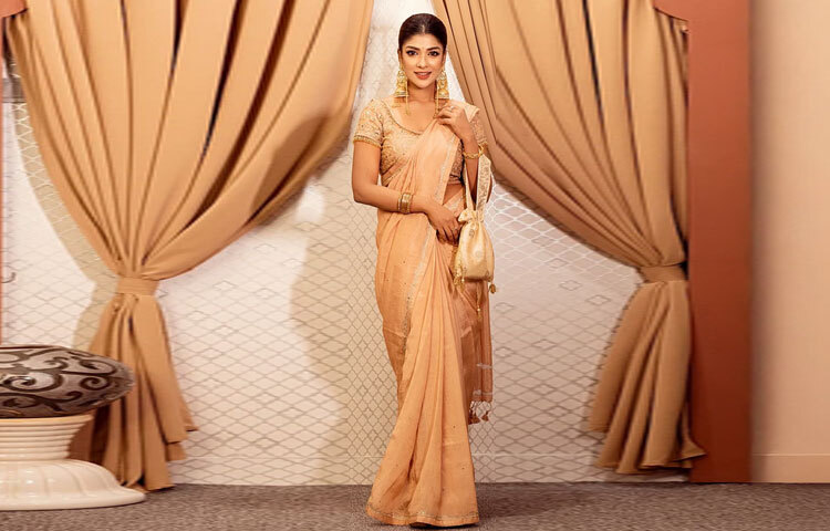 ন্যুড টোনের সিল্ক ফেব্রিকের শাড়িটি যেন পুরো লুকের কেন্দ্রবিন্দু। বর্ডারজুড়ে সোনালি জরির সূক্ষ্ম কারুকাজ এনে দিয়েছে আভিজাত্য।