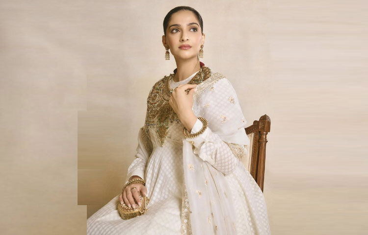 সোনম কাপুরের এই লুকের মূল আকর্ষণ নিঃসন্দেহে তার পোশাকের রং ও টেক্সচার। নিরেট সাদা রঙের ওপর সূক্ষ্ম সোনালি কারুকাজ, পুরো পোশাকে যেন মিশে আছে সৌন্দর্যের মায়া ও ঐতিহ্যের দৃঢ়তা।