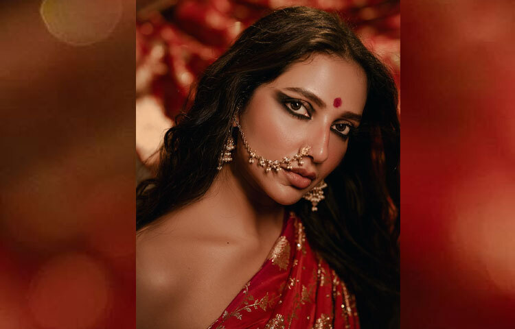 তার সাজগোজে ছিল সাবেকি আভিজাত্যের ছোঁয়া। চোখে কাজল, ঠোঁটে লাল লিপস্টিক, আর মুখে উজ্জ্বলতা-সবকিছু মিলে যেন অনায়াসে বয়ে আনে এক দেবীময় আবেদন। ক্যামেরার সামনে তার আত্মবিশ্বাসী ভঙ্গিমা, মৃদু হাসি ও চোখের গভীরতায় ধরা দিয়েছে এক অন্য রূপ।