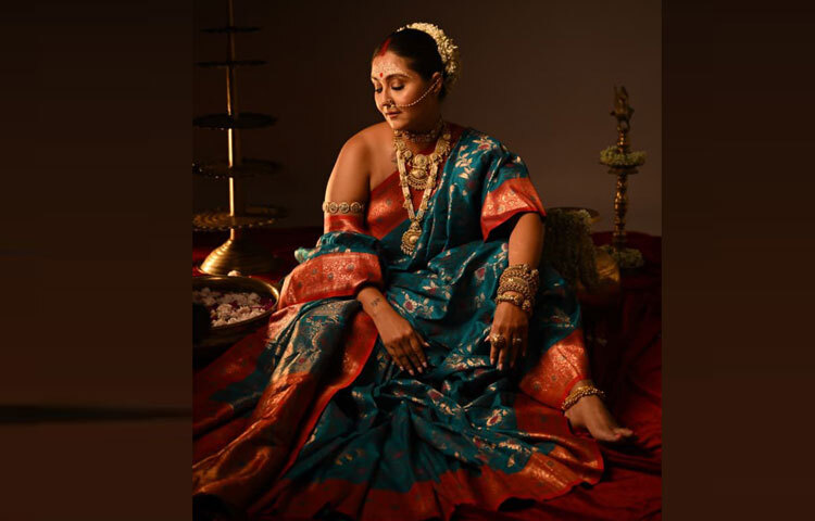 চুলের টানা খোঁপায় গুঁজে নিয়েছেন সাদা ফুলের গাজরা, কপালে চন্দনের নকশা।