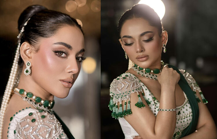 দেশের স্বনামধন্য ডিজাইনার সাফিয়া সাথীর শাড়িতে তমার সাজে এসেছে রাজকীয় আভিজাত্য। পান্না সবুজ একরঙা শাড়ি, সঙ্গে ঝলমলে বিডওয়ার্কের স্টেটমেন্ট ব্লাউজ যেন লুকের কেন্দ্রে। মুক্তা, সাদা ও পান্না পাথরের নিখুঁত কারুকাজে তৈরি এই ব্লাউজ তমার গ্ল্যামারকে দিয়েছে এক অন্য মাত্রা।