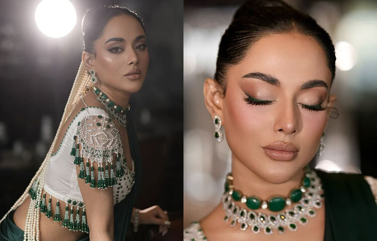 ঠোঁটে হালকা ন্যুড লিপস্টিক, গালে হালকা গোলাপি ব্লাশ আর উজ্জ্বল হাইলাইটারের ছোঁয়া ফুটিয়ে তুলেছে তার সৌন্দর্য। চোখে সবুজ টোনের স্মোকি আইশ্যাডো আর নাটকীয় আইলাইনারে বেড়েছে মাদকতা।