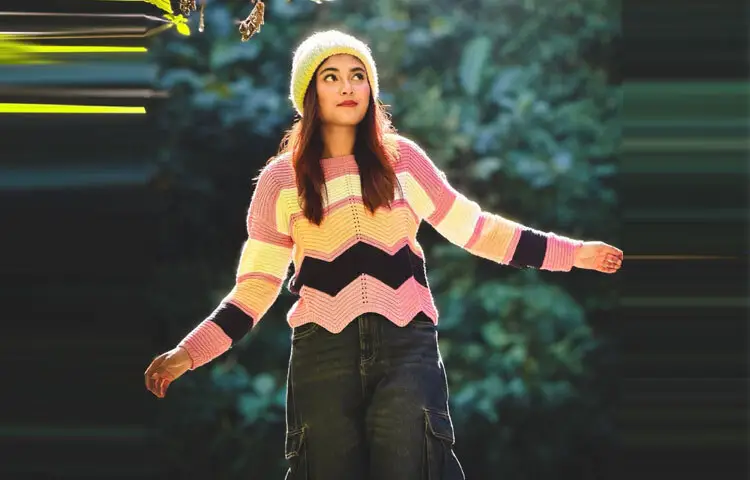 প্রথমেই চোখে পড়ে তার রঙিন নিট সোয়েটার। গোলাপি, হালকা হলুদ, সাদা ও কালোর জিগজ্যাগ প্যাটার্ন যেন শীতের নিস্তব্ধতায় রঙের ঢেউ। সাধারণত শীতের পোশাকে গাঢ় রঙের আধিপত্য থাকলেও তটিনীর এই পছন্দ সাহসী ও আনন্দমুখর।