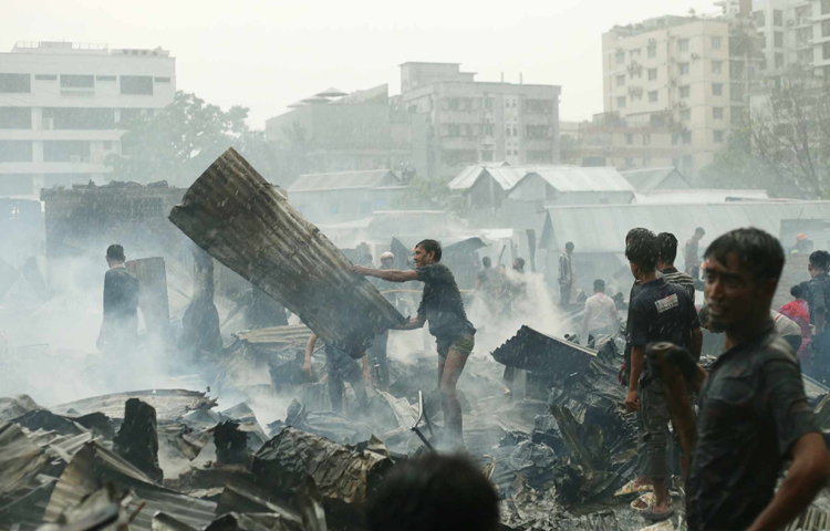পুড়ে যাওয়া ঘরগুলোতে নিজেদের কোনো কিছু অবশিষ্ট আছে কি না, তা খুঁজে দেখছেন অনেকে। ছবি: মাহবুব আলম