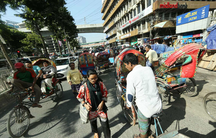 তবে এই নিস্তব্ধতার মধ্যে কাওরানবাজার দেখিয়েছে ভিন্ন এক চিত্র। শাটডাউন কর্মসূচী থাকা সত্ত্বেও সকালে সেখানে দেখা যায় স্বাভাবিকের চেয়েও বেশি মানুষের চলাচল। সকাল ৯টা ২০ মিনিটে তোলা ছবিতে ধরা পড়ে কর্মদিবসের সাধারণ ব্যস্ততা;  রিকশা, বাস, মোটরবাইক, প্রাইভেটকার সবই ছিল ছন্দে। অফিসগামী মানুষের ভিড়ও ছিল স্পষ্ট। যেন শাটডাউনের কোনো ছায়াই সেখানে পড়েনি। রাজধানীর বাণিজ্যিক গুরুত্ব ও দৈনন্দিন দায়বদ্ধতাই হয়তো কাওরানবাজারকে আজও সচল রেখেছে।