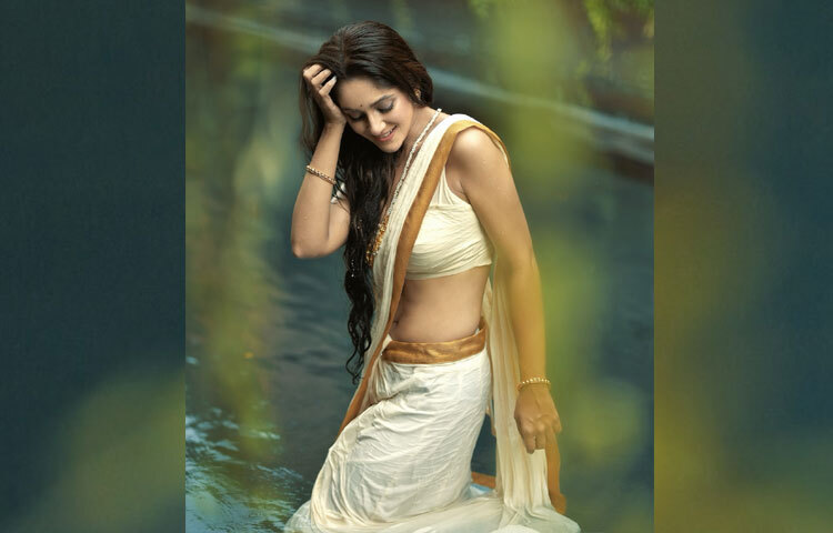 সরু সোনালি পাড়ের সাদা সুতি শাড়ি আর তার সঙ্গে মানানসই স্লিভলেস ছোট ব্লাউজ যেন তার আবেদনকে আরও বাড়িয়ে তুলেছে। কুচলা তলের জলরাশি বরং হয়ে উঠেছে তার লুকের পটভূমি, যেখানে তৃণার সৌন্দর্যই ভেসে বেড়াচ্ছে।