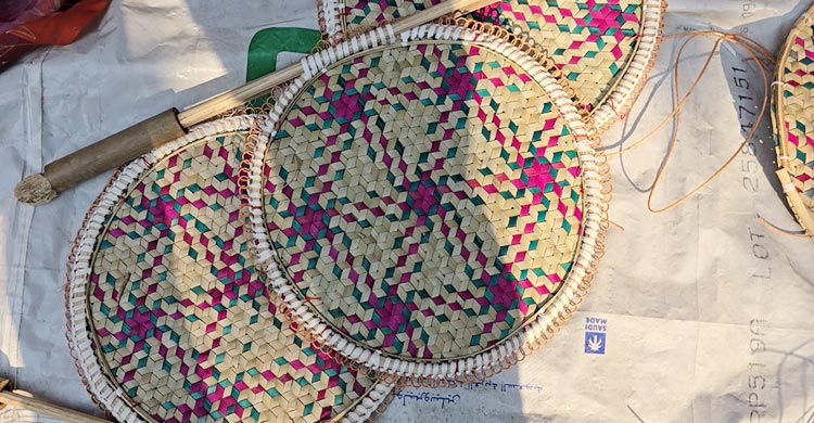 ঘরের আঙিনায় কয়েকজন একসঙ্গে বসে তৈরি করছেন হাতপাখা। এরমধ্যে কেউ তালপাতা চিরিয়ে নিচ্ছেন