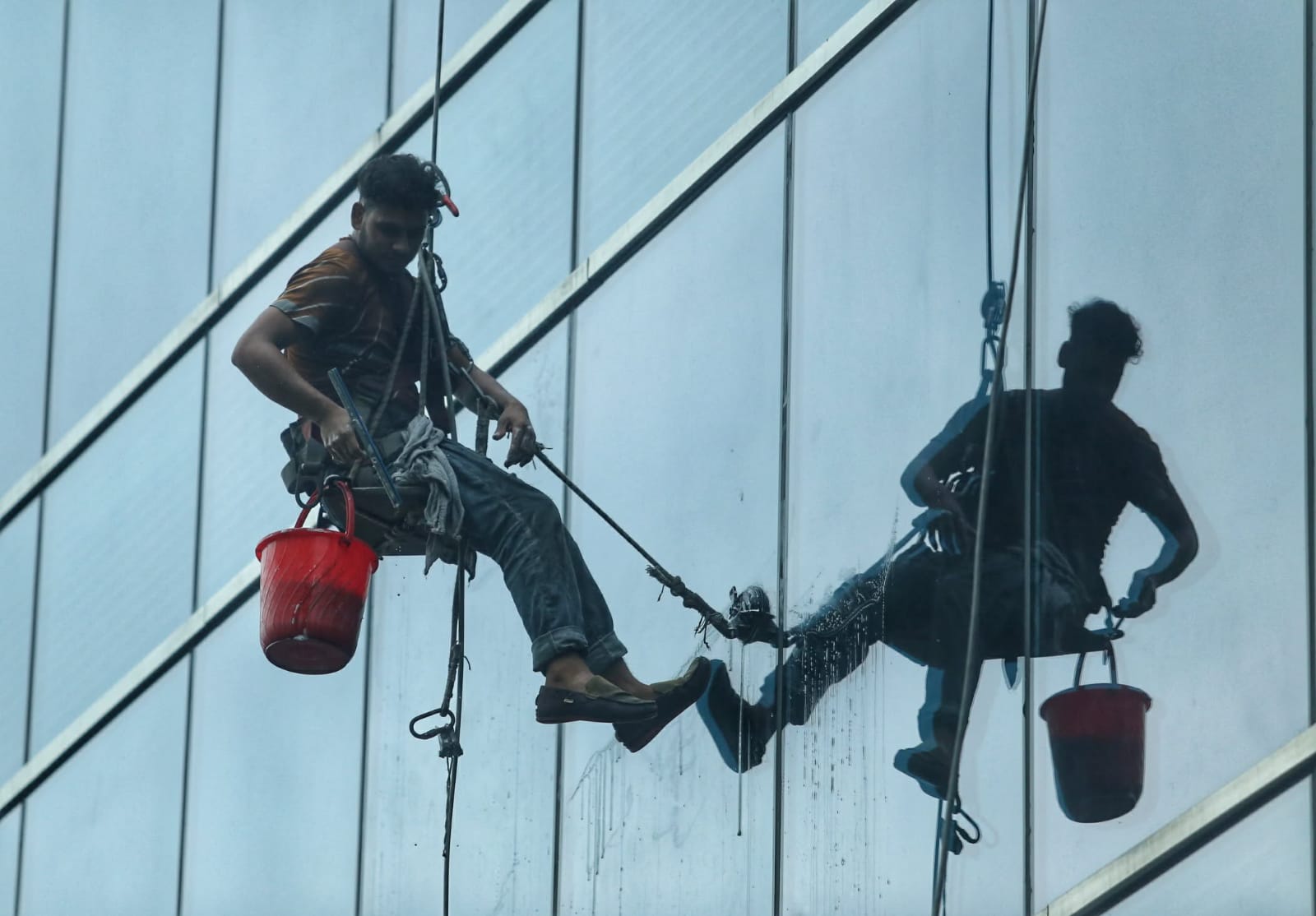 বহুতল ভবনের কাঁচ পরিষ্কার করেছেন এক শ্রমিক