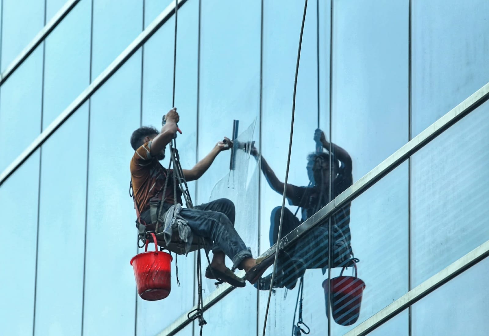 বহুতল ভবনের কাঁচ পরিষ্কার করেছেন এক শ্রমিক